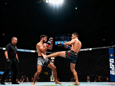 UFC八角笼中两位格斗选手激烈对决的场面，裁判紧盯着双方动作，现场灯光聚焦在擂台中央